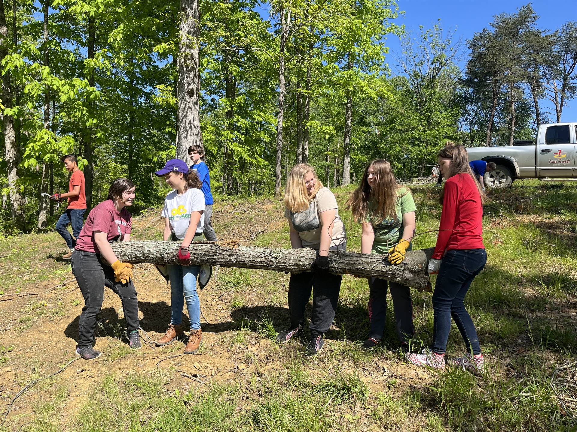 Students working to clear trees and debris at a local camp